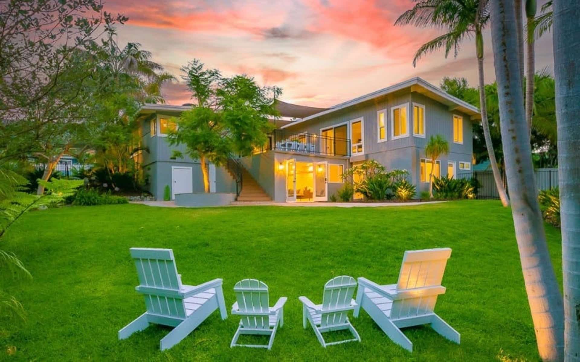 Exterior of a Solana Beach vacation rental showing a covered carport and driveway, surrounded by palm trees and lush landscaping. (property managed by thecoastalproject.com)