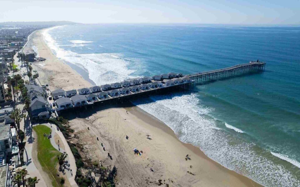 Crystal Pier & Pacific Beach – Iconic San Diego Coastal Living Aerial view of Pacific Beach and Crystal Pier in San Diego, with oceanfront cottages extending over the water and waves crashing along the sandy shoreline