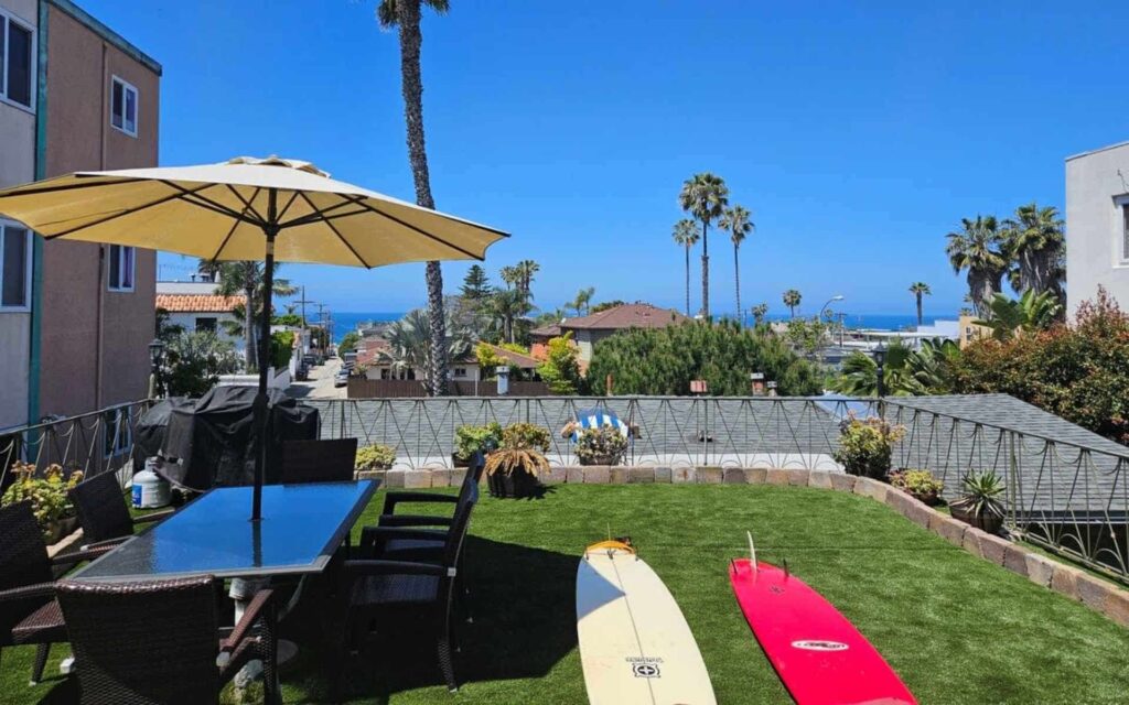 self managed vacation rental coastal property Ocean-view vacation rental patio with surfboards and outdoor dining