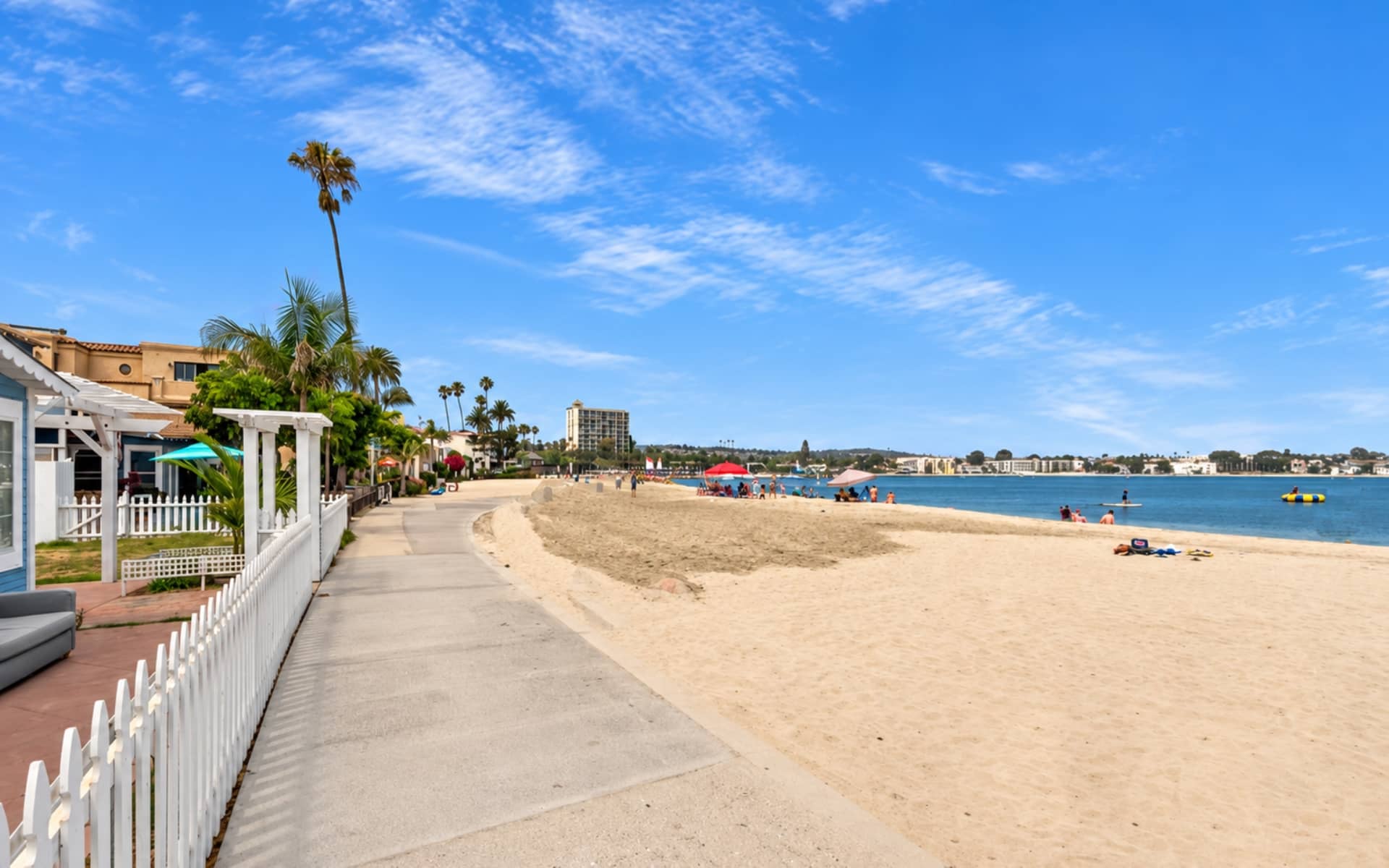 Bayfront homes beside a waterfront walkway and sandy beach in Mission Beach, San Diego