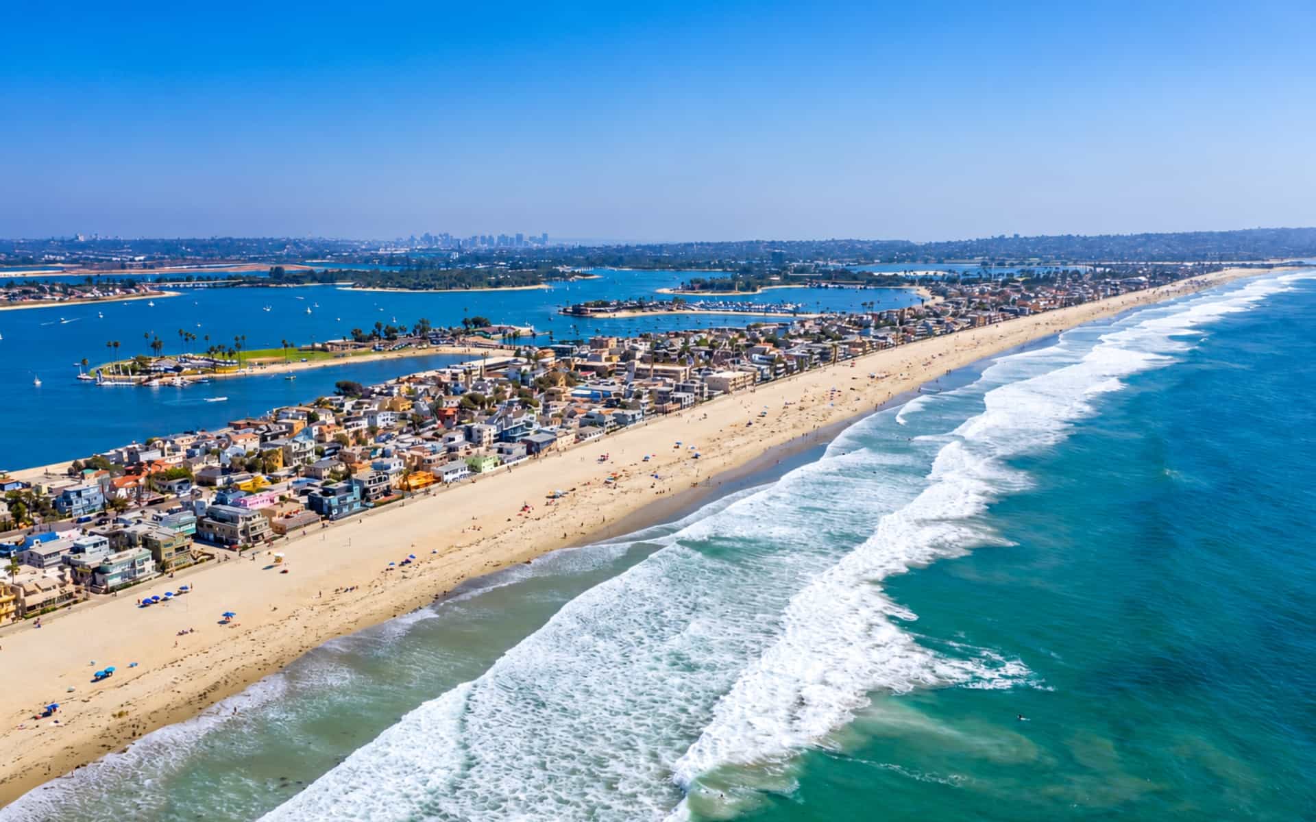 Aerial view of Mission Beach coastal homes and sandy beach between Mission Bay and the Pacific Ocean.