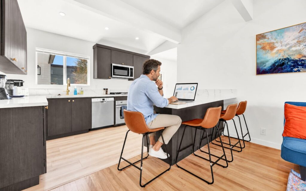 Vacation Rental Owner Reviewing Management Performance Vacation rental owner reviewing property management performance on a laptop inside a San Diego rental.