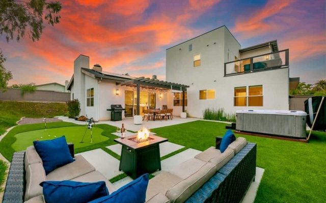 Modern Oceanside vacation home with outdoor lounge, fire pit, putting green, and spa at sunset
