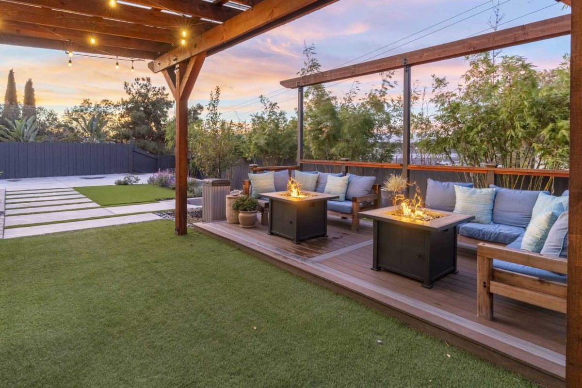 Stylish backyard with pergola-covered lounge, dual fire pits, and modern landscaping perfect for short-term stays.